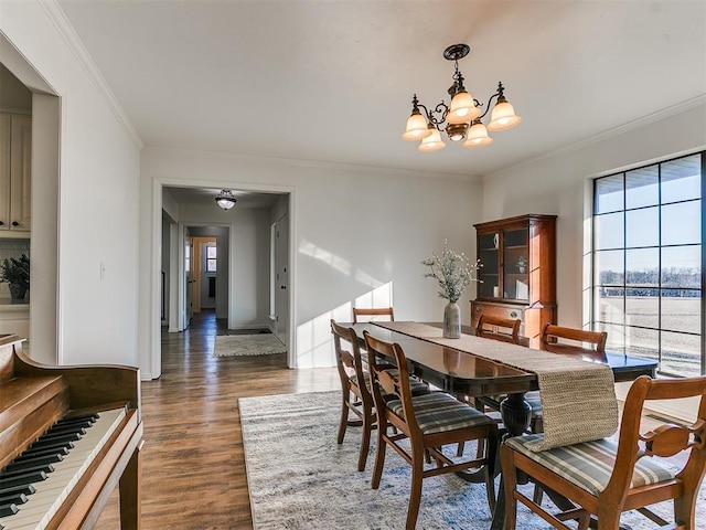 dining area featuring ornamental molding, a notable chandelier, baseboards, and wood finished floors