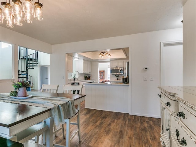 dining room featuring stairs, a tray ceiling, dark wood-type flooring, and a notable chandelier