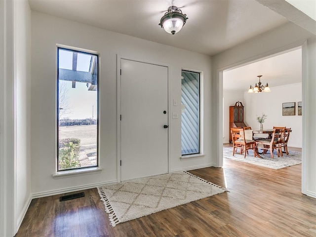 entryway with a notable chandelier, baseboards, visible vents, and wood finished floors