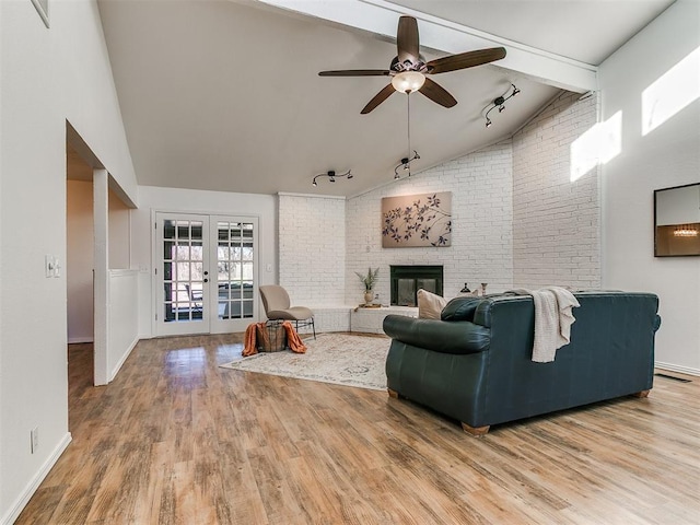 living area featuring a fireplace, beamed ceiling, wood finished floors, and french doors