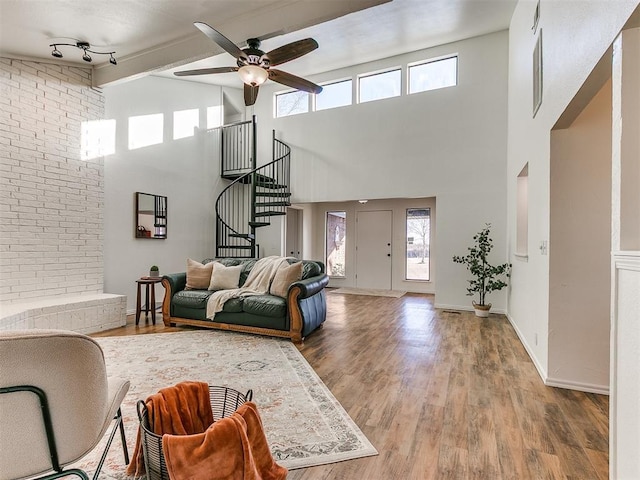 living area with a ceiling fan, baseboards, stairway, and wood finished floors