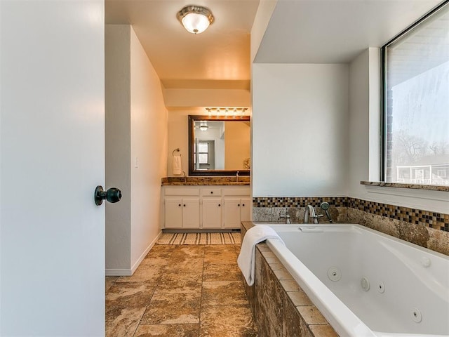 full bathroom with a tub with jets and vanity