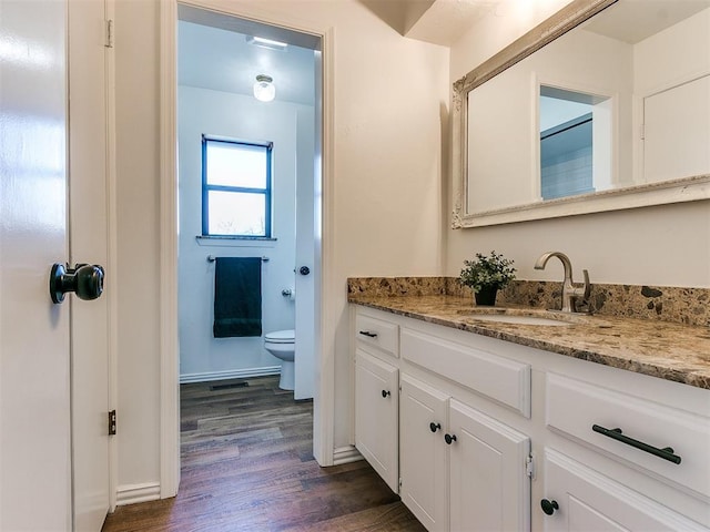 bathroom featuring baseboards, vanity, toilet, and wood finished floors