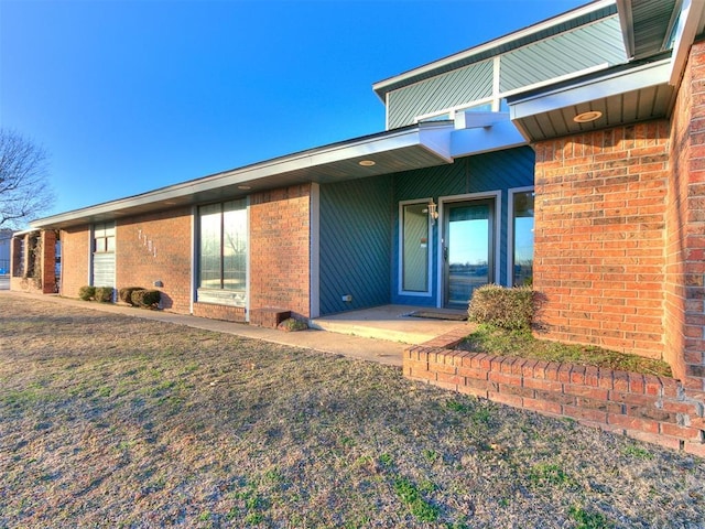 view of exterior entry featuring brick siding