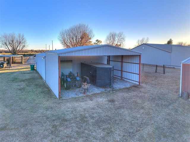 view of pole building featuring driveway, a lawn, and fence