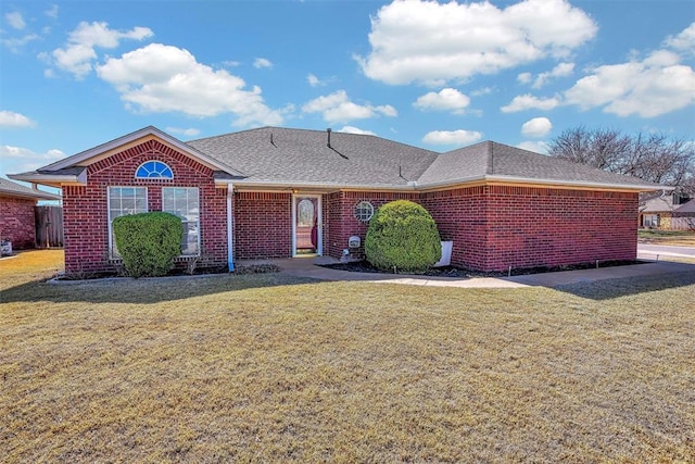 single story home featuring a front yard, brick siding, and a shingled roof