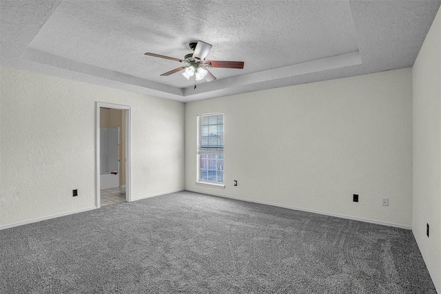 carpeted spare room featuring a ceiling fan, a raised ceiling, a textured wall, and a textured ceiling