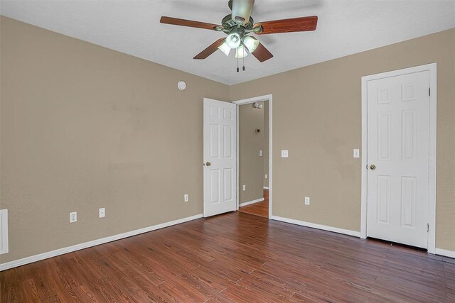 spare room featuring a ceiling fan, baseboards, and dark wood-type flooring