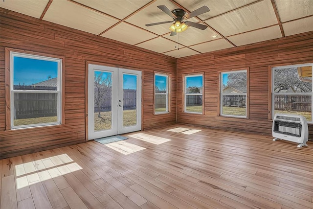 unfurnished sunroom featuring ceiling fan, french doors, and heating unit