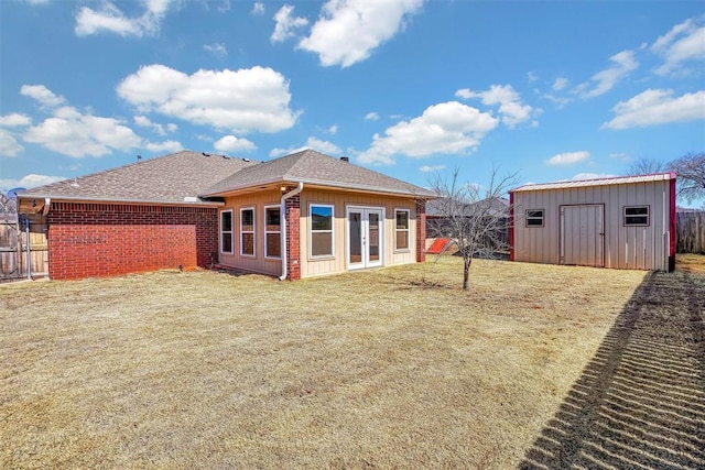 back of house with an outbuilding, brick siding, a yard, french doors, and a storage unit