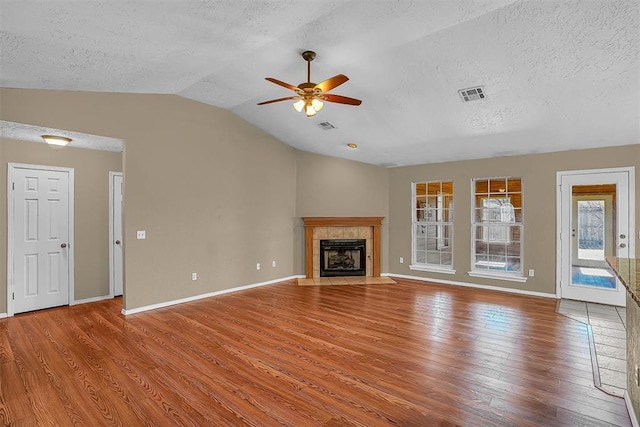 unfurnished living room featuring visible vents, wood finished floors, a fireplace, and vaulted ceiling