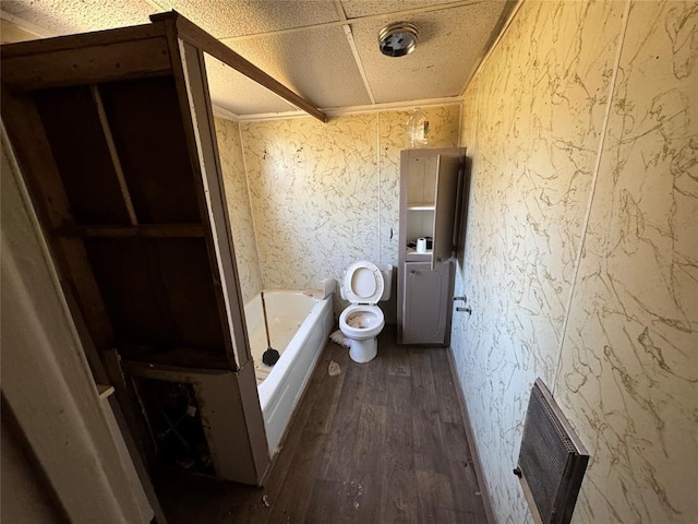 bathroom with toilet, wood finished floors, visible vents, ornamental molding, and a bathtub