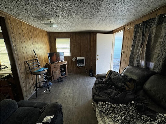 interior space featuring a textured ceiling, wood walls, wood finished floors, and heating unit