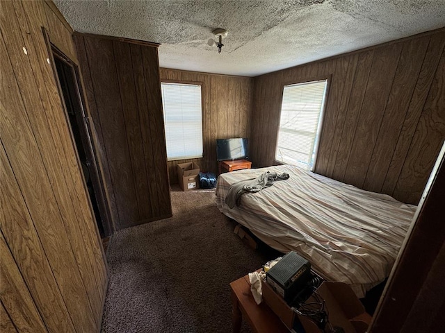 bedroom featuring carpet floors, wooden walls, and a textured ceiling
