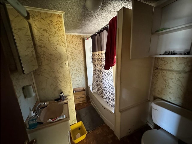 interior space with wallpapered walls, toilet, vanity, shower / bath combination with curtain, and a textured ceiling