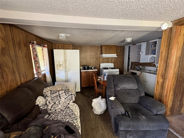 living area with a textured ceiling, dark wood-type flooring, and wooden walls