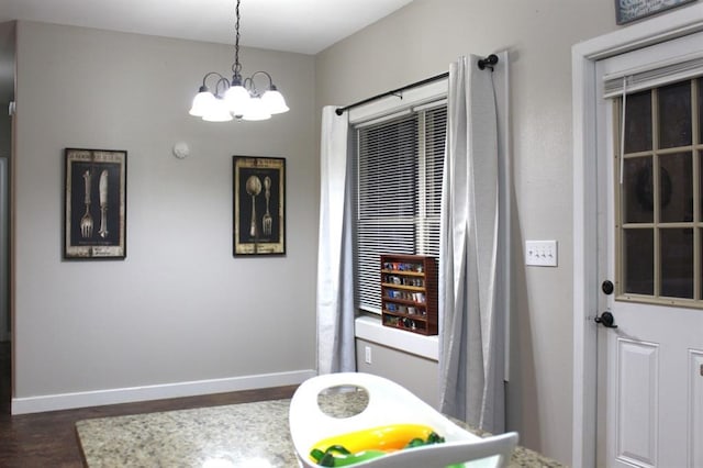 interior space featuring dark wood-type flooring, a chandelier, and baseboards