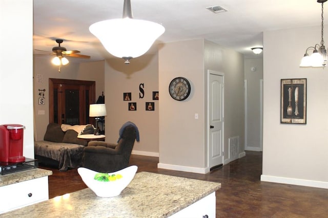 living room with ceiling fan with notable chandelier, concrete floors, visible vents, and baseboards