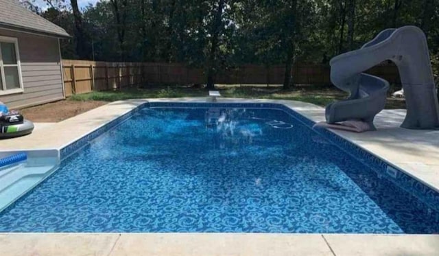 view of swimming pool with a fenced backyard, a water slide, and a patio