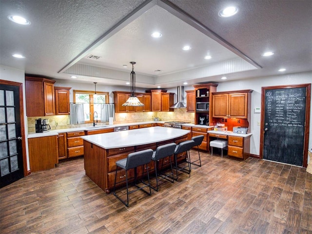 kitchen with light countertops, wall chimney range hood, a spacious island, and a kitchen breakfast bar