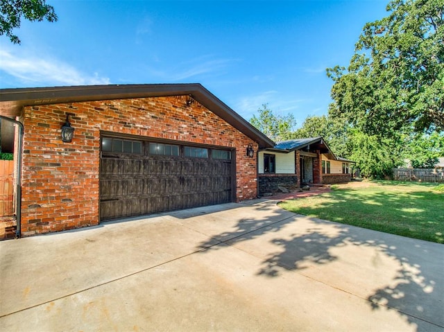 view of front of house featuring a garage, concrete driveway, fence, a front lawn, and brick siding