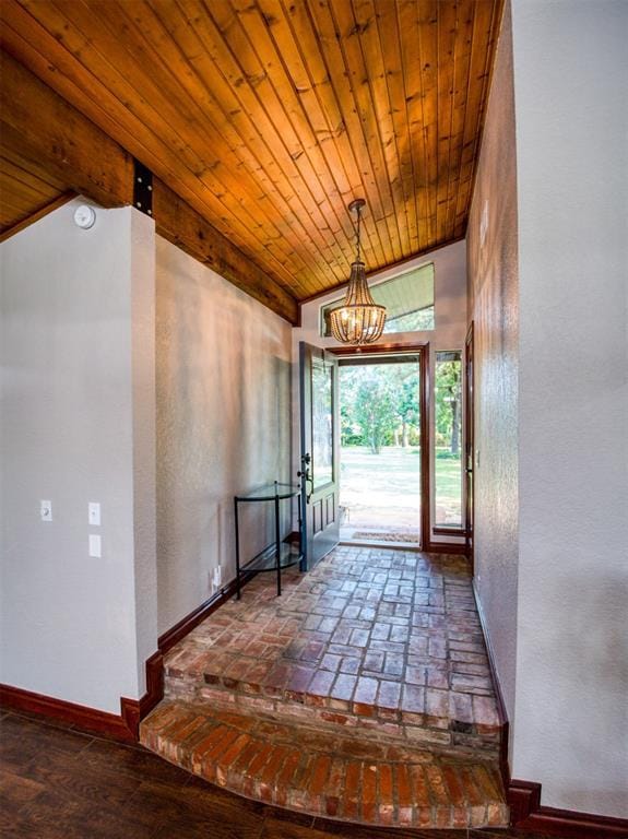 interior space featuring lofted ceiling, an inviting chandelier, wood ceiling, and baseboards