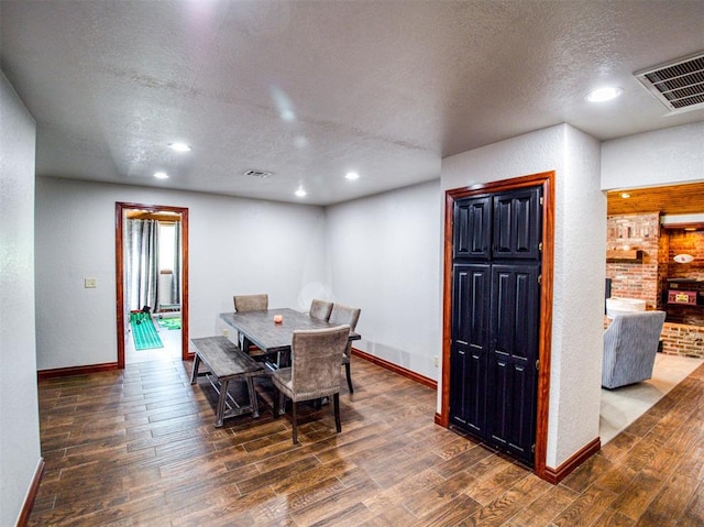 dining space featuring dark wood-style floors, baseboards, visible vents, and a textured ceiling