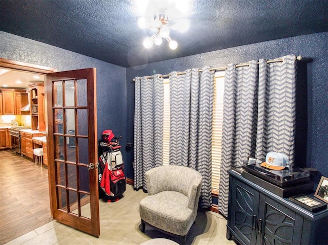 sitting room featuring french doors, built in study area, a textured wall, and a textured ceiling