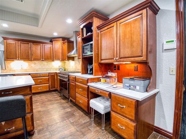 kitchen with light countertops, appliances with stainless steel finishes, dark wood-type flooring, and wall chimney range hood