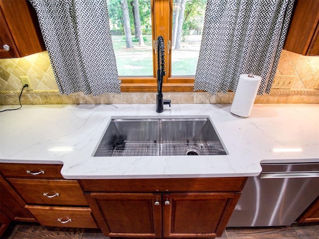 interior details featuring dishwasher, light stone counters, a sink, and tasteful backsplash