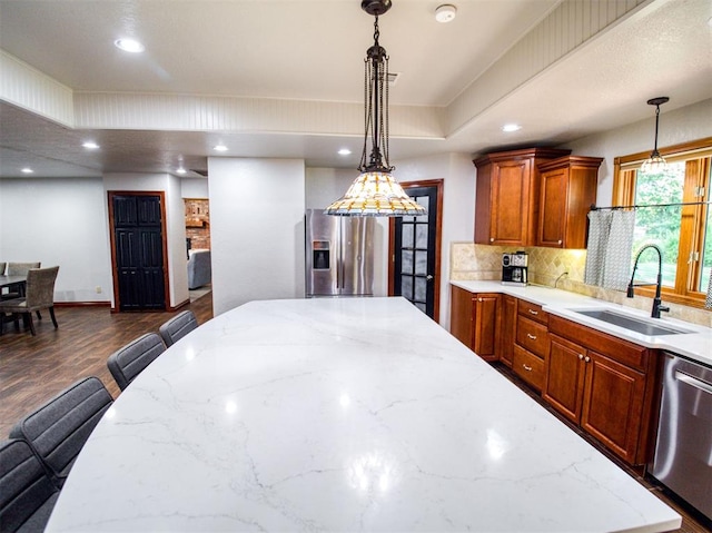 kitchen featuring appliances with stainless steel finishes, a sink, hanging light fixtures, and a kitchen bar