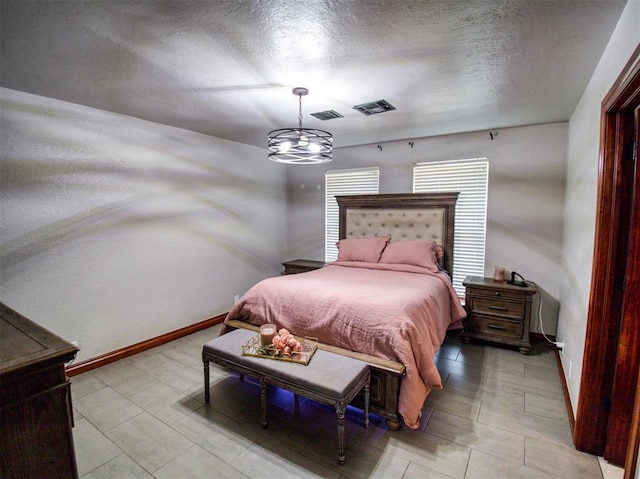 bedroom with a textured ceiling, visible vents, and baseboards