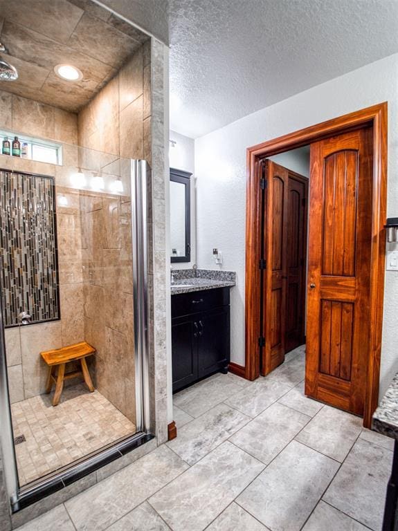 bathroom with a textured ceiling, a shower stall, and vanity