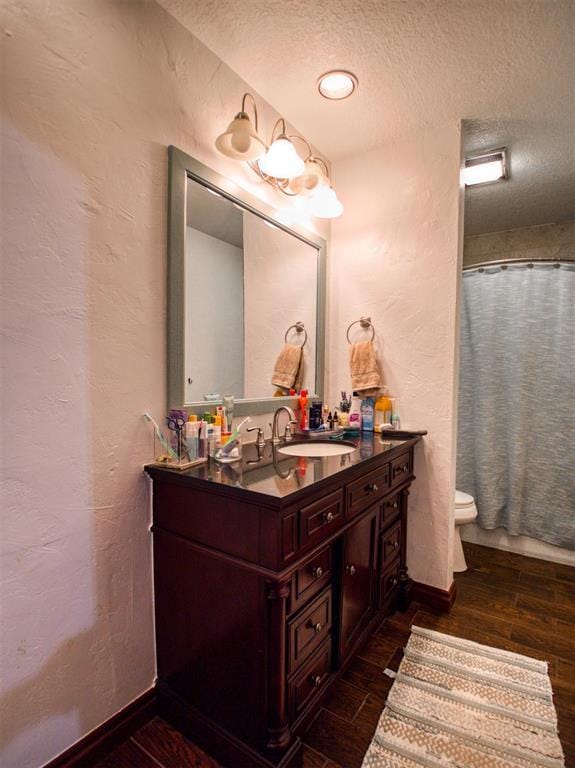 full bathroom with a textured ceiling, vanity, wood finished floors, and a textured wall