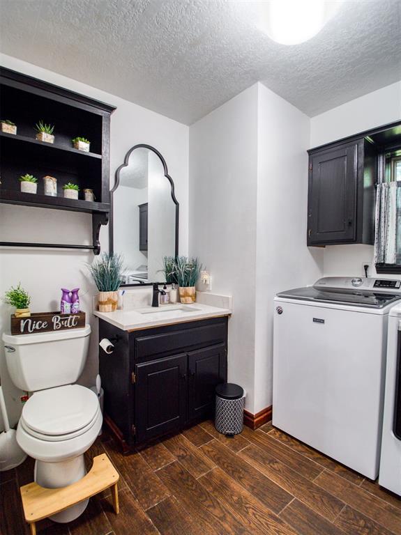 bathroom featuring toilet, vanity, washer and dryer, and wood finish floors