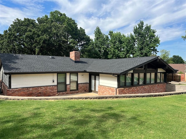 view of front of house with a front yard, brick siding, and a chimney