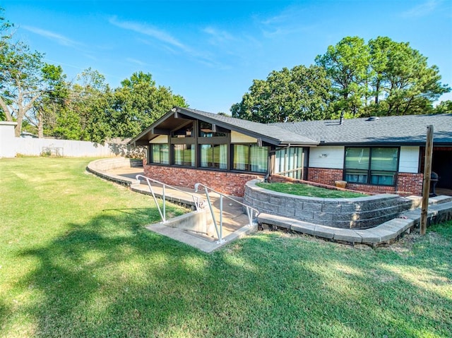 rear view of house with brick siding, fence, a lawn, and a patio