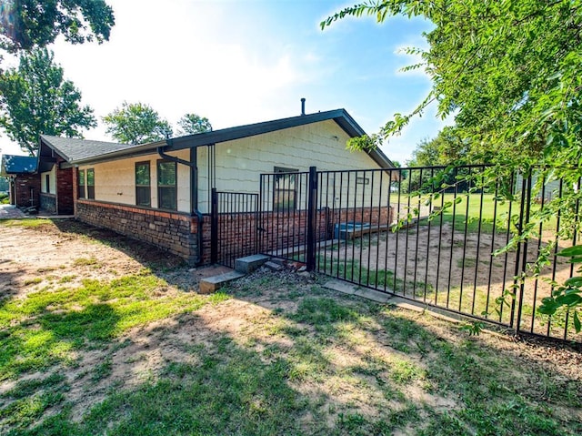 view of side of home featuring stone siding, fence, and a lawn