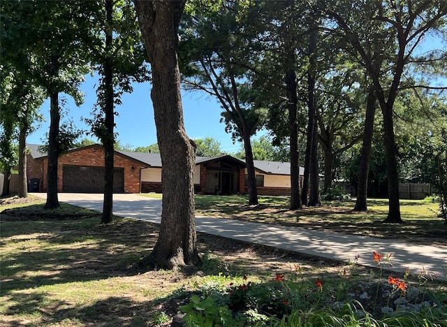 exterior space featuring concrete driveway, brick siding, fence, and a garage