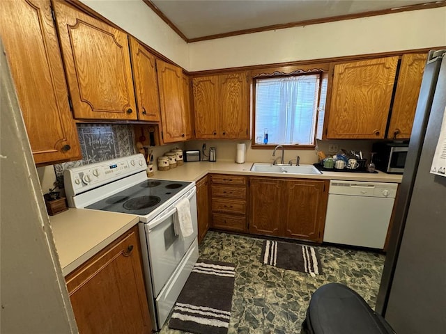 kitchen with light countertops, brown cabinetry, ornamental molding, a sink, and white appliances