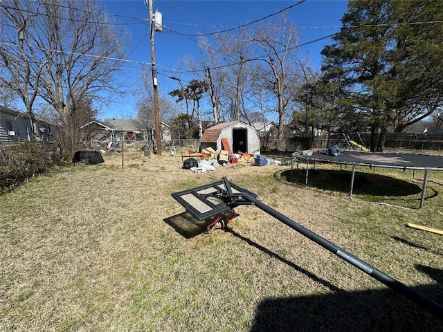 view of yard with a storage unit, a trampoline, an outdoor structure, and a fenced backyard