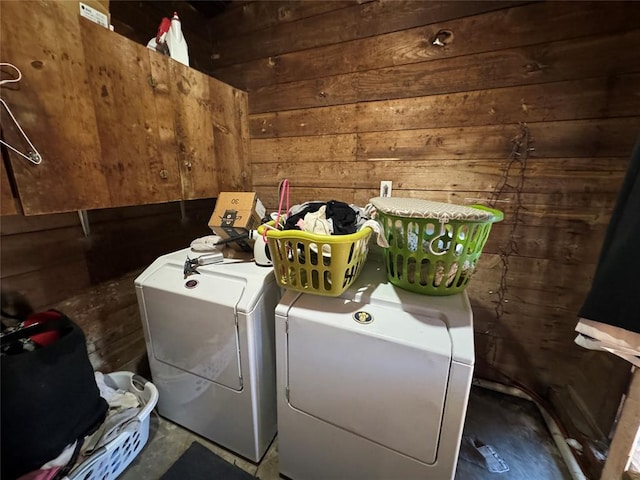 clothes washing area with wooden walls, laundry area, and washer and clothes dryer