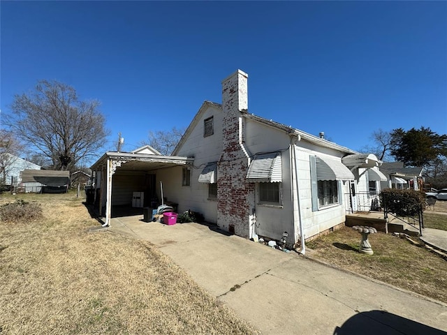 exterior space with an attached carport, driveway, and a chimney