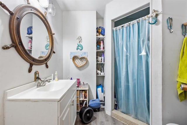 bathroom with wood finished floors, a shower stall, and vanity