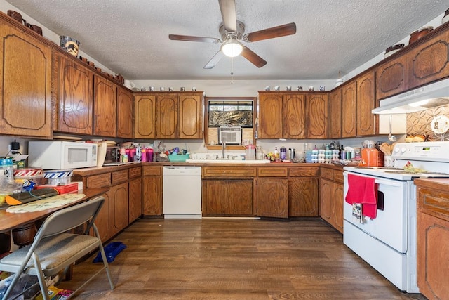 kitchen with dark wood-style flooring, brown cabinetry, a textured ceiling, white appliances, and under cabinet range hood