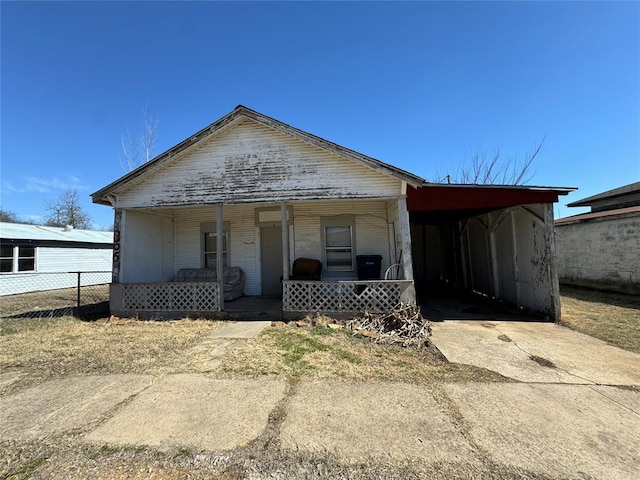 bungalow-style home with concrete driveway, a porch, and fence