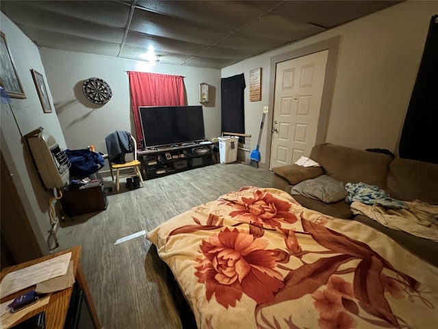 bedroom featuring a drop ceiling and wood finished floors