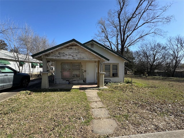 bungalow-style house featuring a front lawn, concrete block siding, and a porch