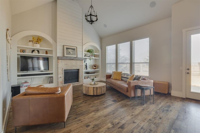 living room with built in features, a brick fireplace, high vaulted ceiling, and wood finished floors