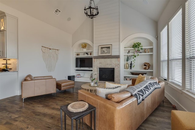 living room with visible vents, high vaulted ceiling, built in features, a fireplace, and dark wood-style flooring